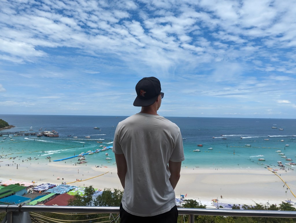 Ein junger Mann blickt von einem Aussichtspunkt auf den Strand in Koh Samed